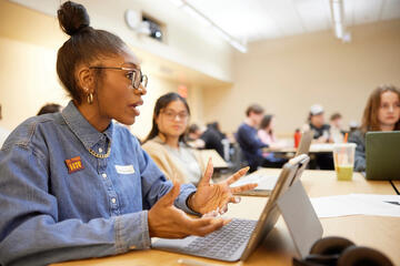 A student talking in a group setting with her laptop.